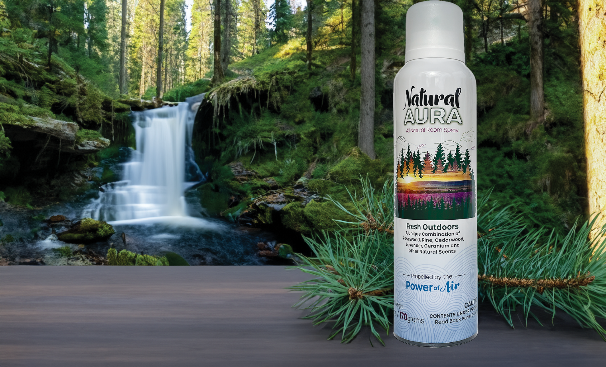 bottle of Natural Aura Fresh Outdoors room spray with a waterfall cutting through the forest with pine trees and soft velvety moss in the background.
